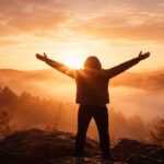 Imagen simbólica de una persona sosteniendo los brazos en alto al amanecer, representando la fe que permanece aun en medio del cansancio.